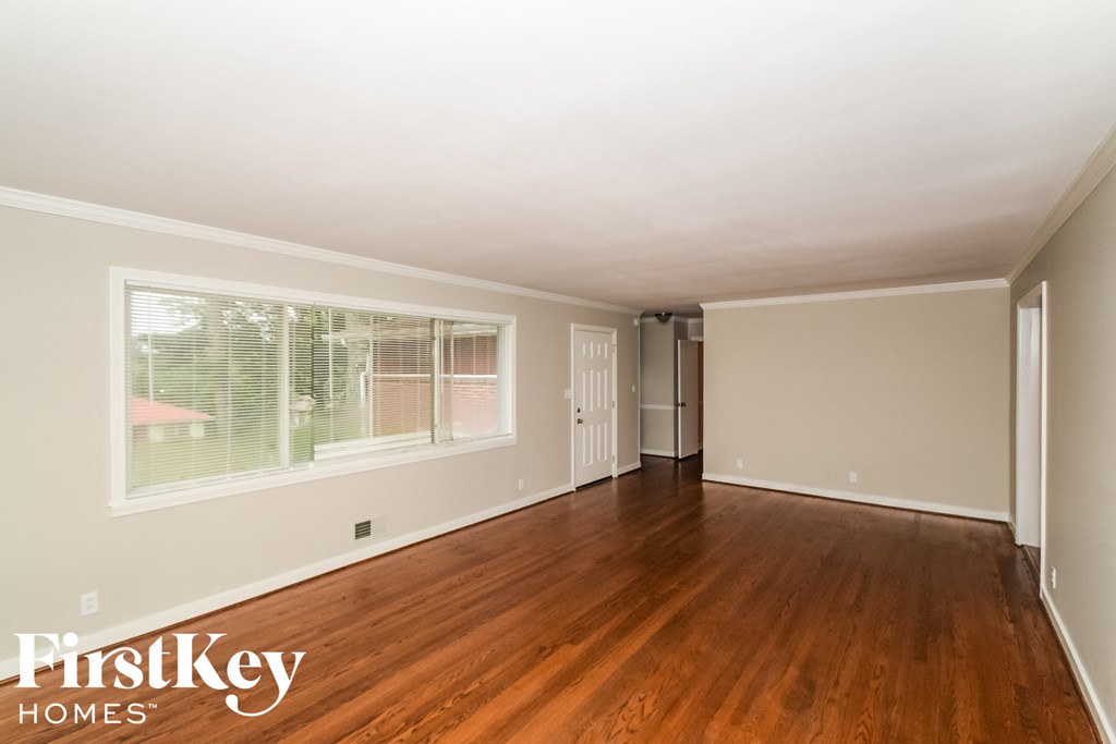 the living room of a home with wood floors and a large window