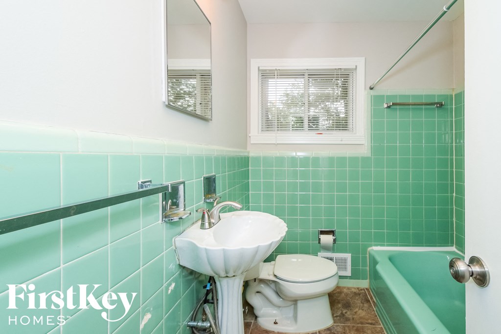 a green and white bathroom with a sink and toilet and a tub
