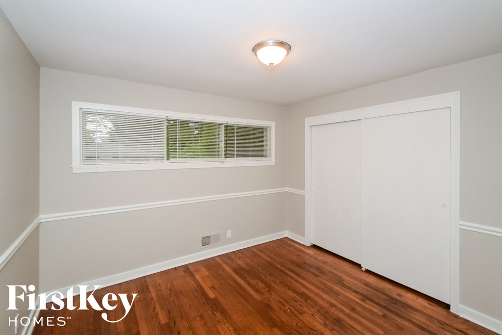 a bedroom with wood flooring and white walls and a window