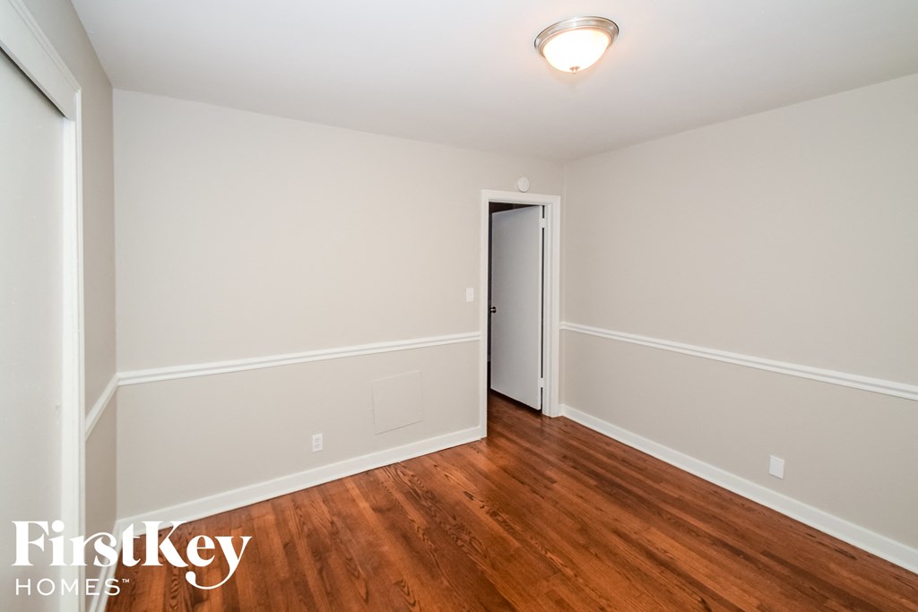 a bedroom with wood flooring and white walls and a door