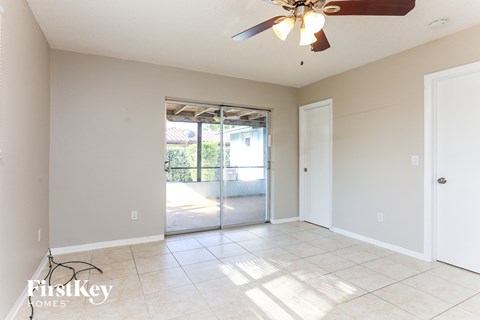A spacious room with a ceiling fan and sliding glass doors leading to a balcony.