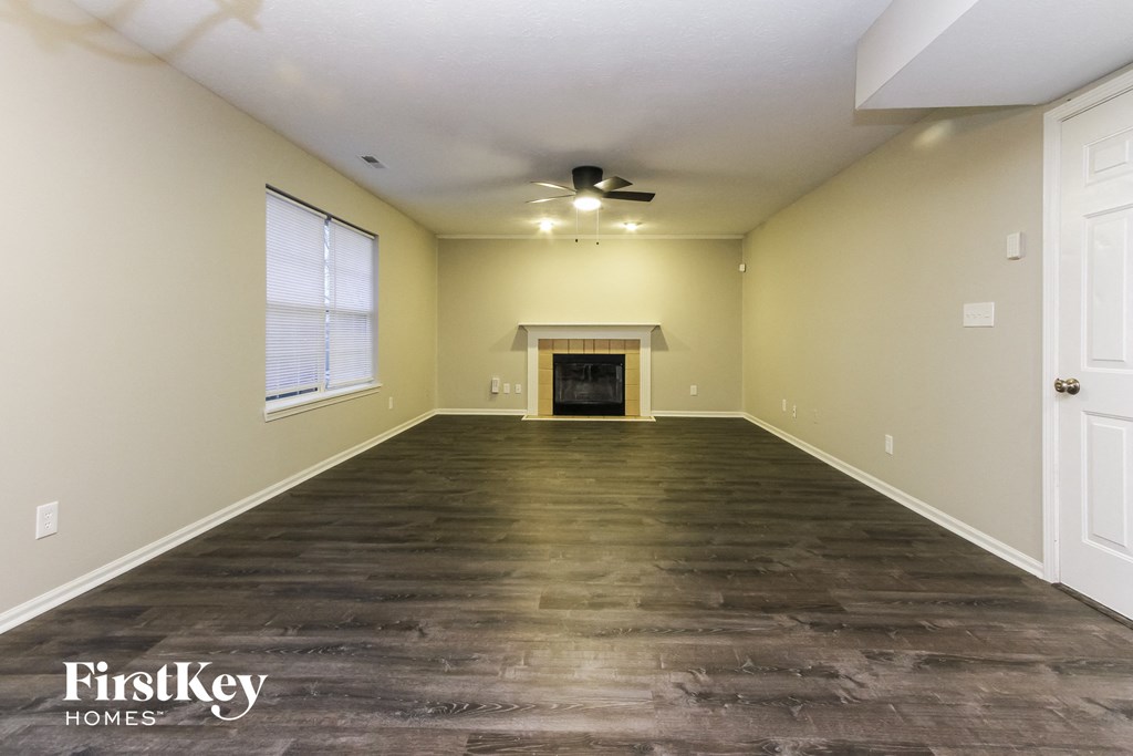 the living room with wood floors and a fireplace