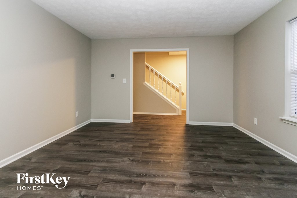 an empty living room with wood floors and a staircase