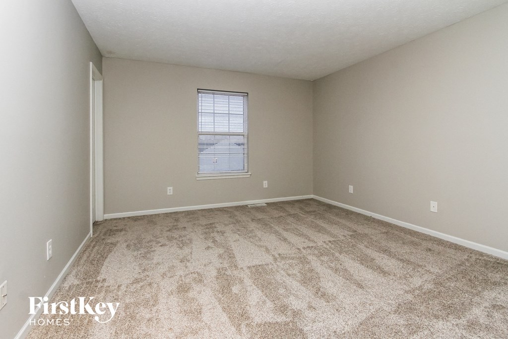 a spacious bedroom with carpeted flooring and a window