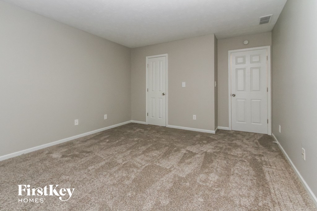 the upstairs bedroom with carpeted flooring and white doors