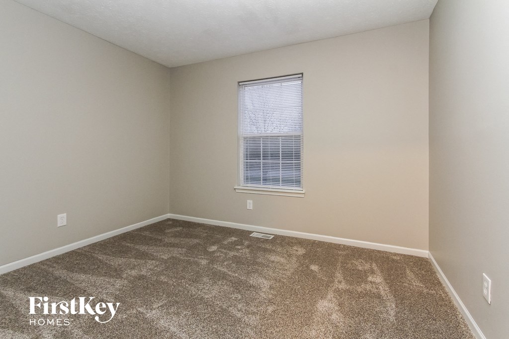 a spacious room with carpet and a window