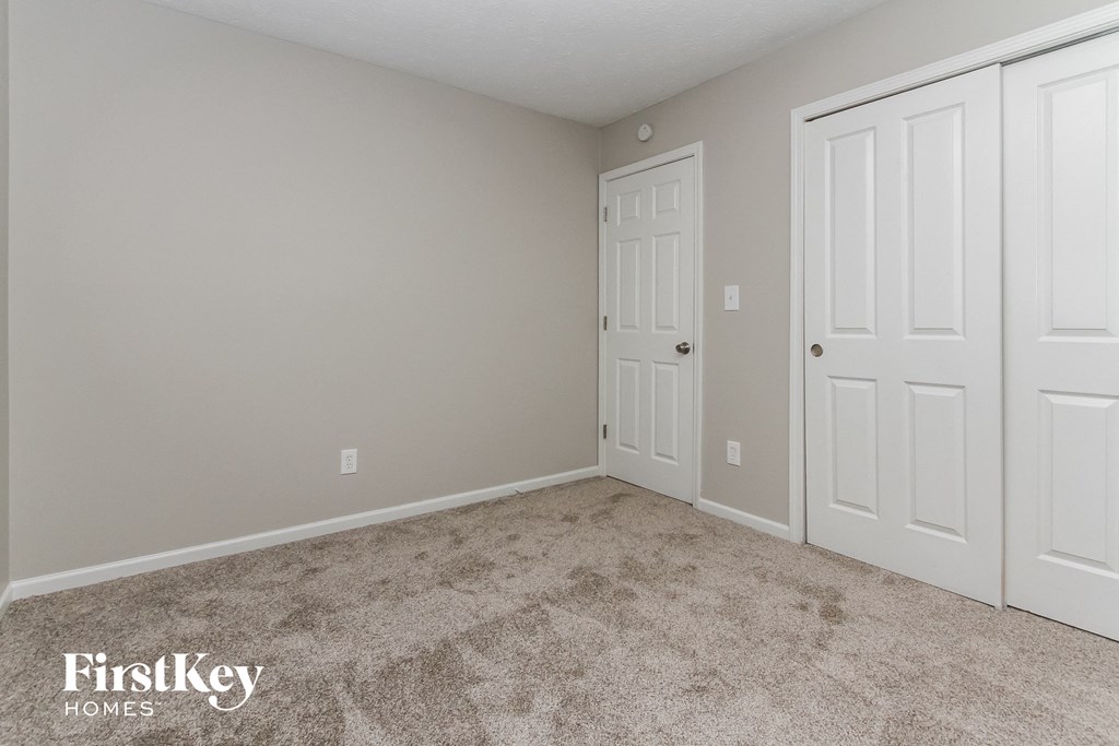 a bedroom with two doors and a carpeted floor