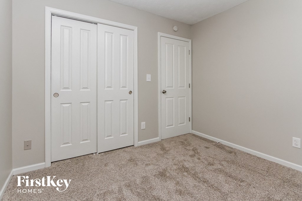 a bedroom with two closets and a carpeted floor