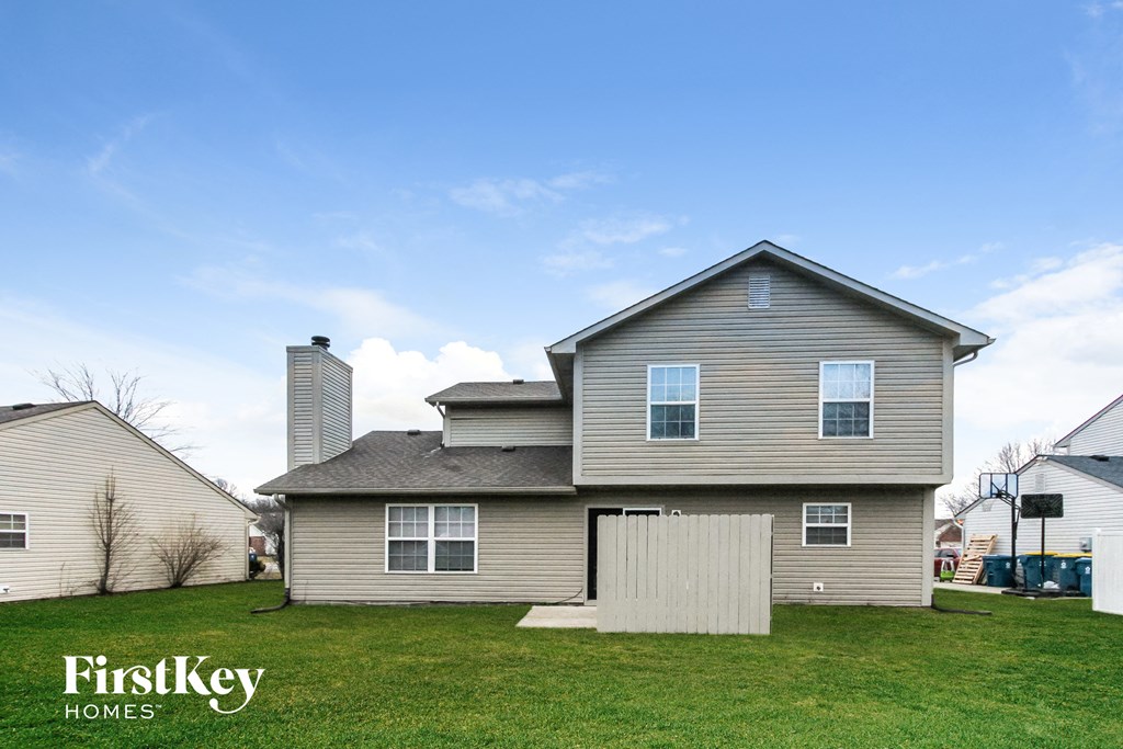 a house with a wooden fence in front of a green yard