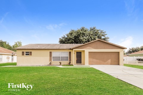 a beige house with a lawn and a driveway