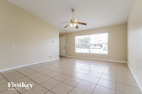 a spacious living room with tiled flooring and a ceiling fan