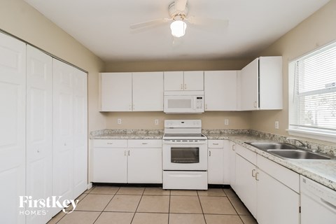 a kitchen with white cabinets and white appliances and a sink