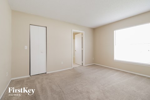 a spacious living room with carpet and a door to a closet
