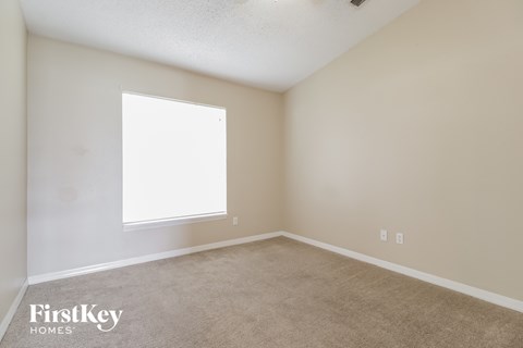 a bedroom with a large window and a carpeted floor