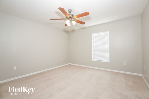 the spacious living room has a ceiling fan and beige carpet
