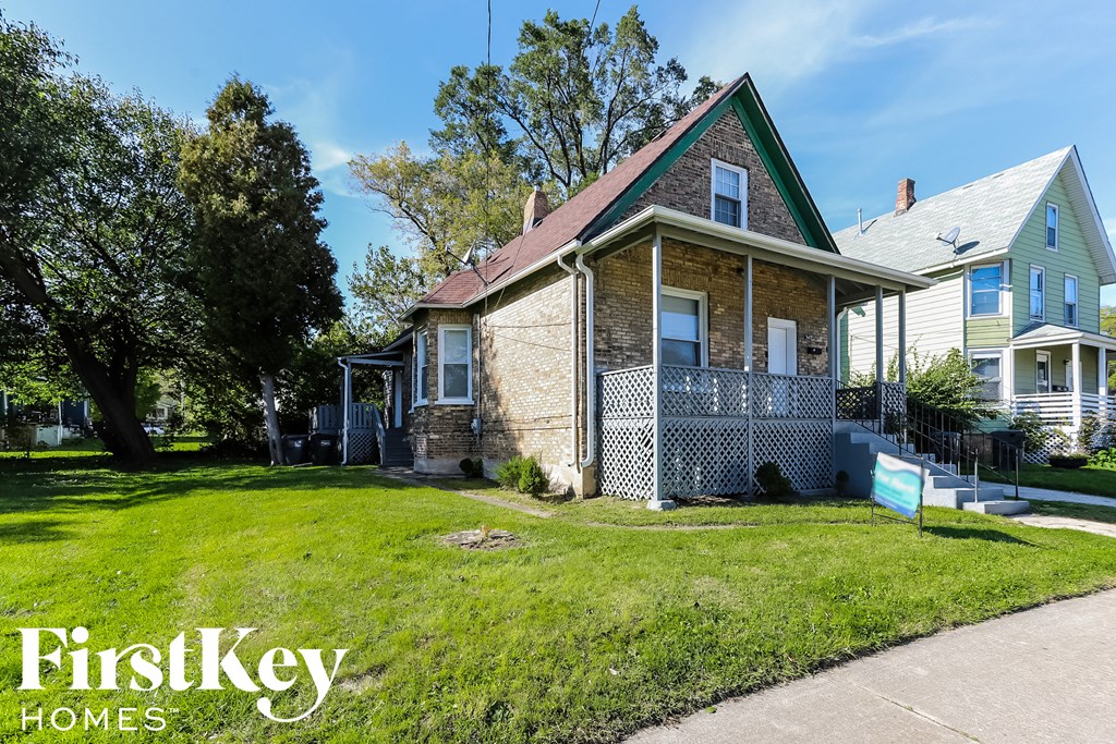 a brick house with a porch and a lawn