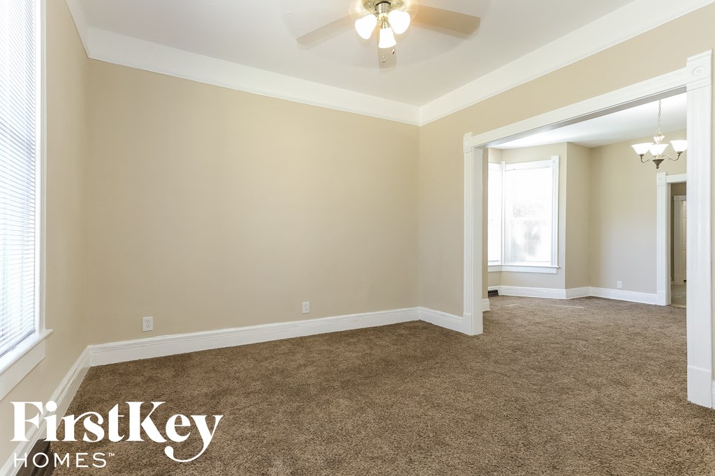 a living room with carpet and a ceiling fan