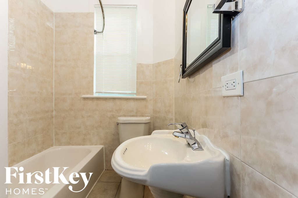 a small bathroom with a sink and a tub and a mirror