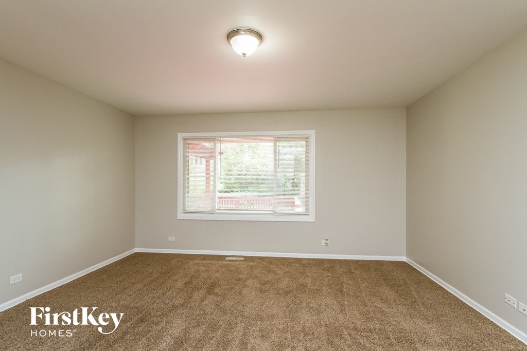the spacious living room with carpet and a window