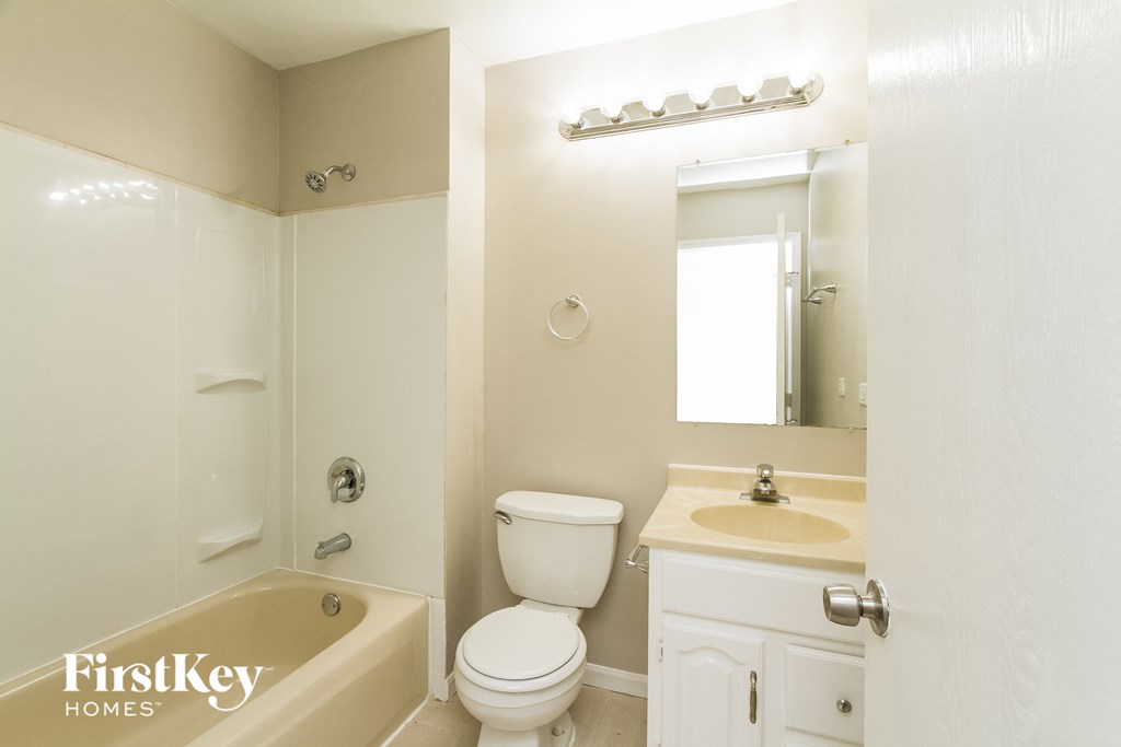 a bathroom with a toilet sink and tub and a mirror