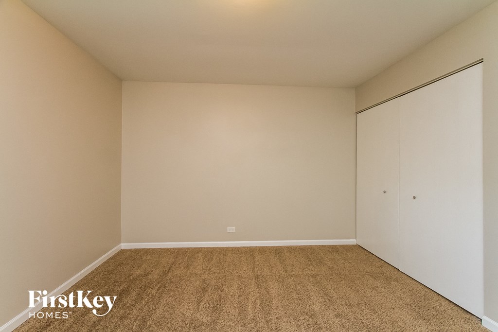 a bedroom with white walls and carpet and a closet