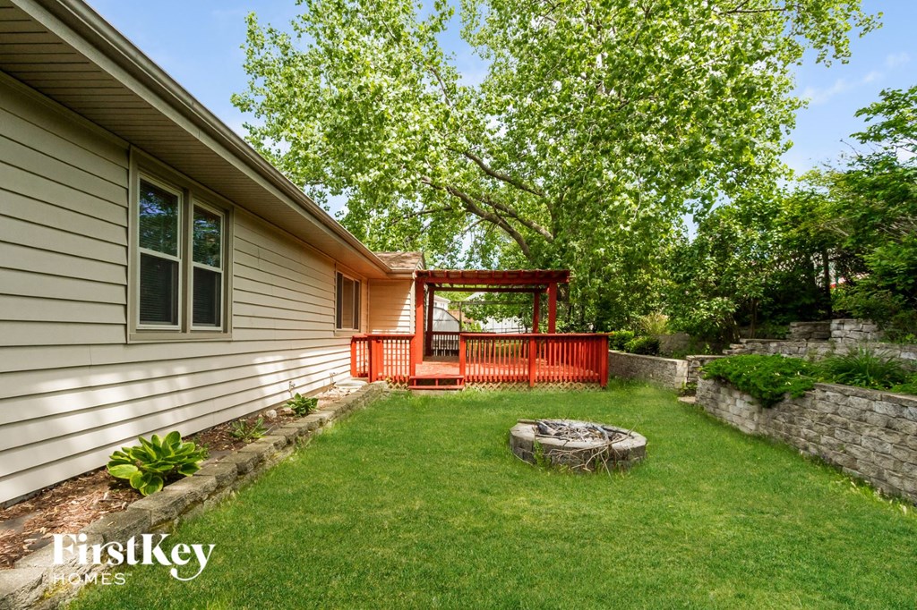 a backyard with a red deck and a fire pit