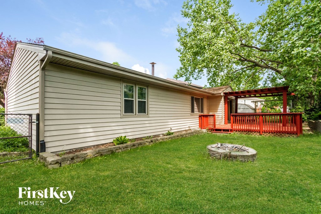 a backyard with a white house and a red deck