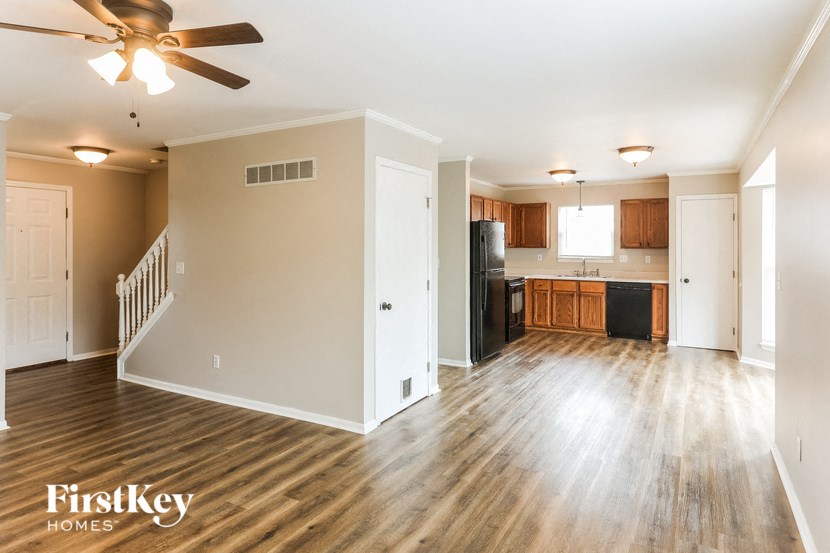 an empty living room and kitchen with a ceiling fan