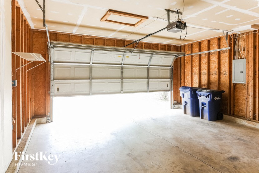 a garage with a white door and two trash cans