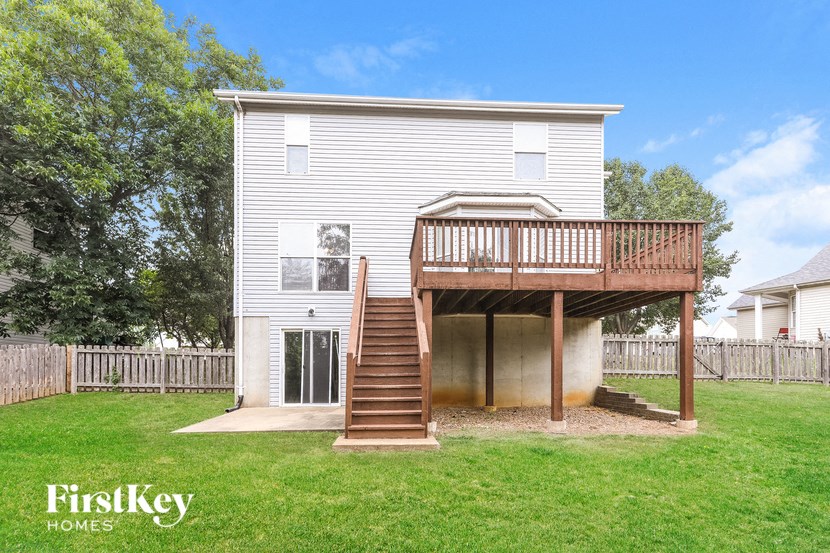 a house with a deck on top of a backyard