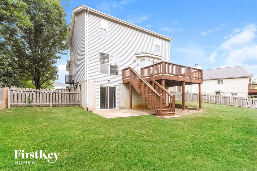 a white house with a wooden deck on top of a yard