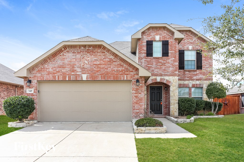 a brick house with a garage door and a lawn