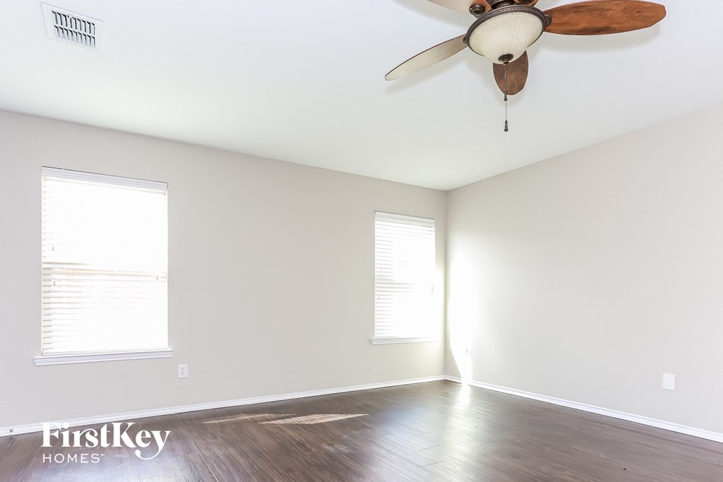 a living room with white walls and a ceiling fan