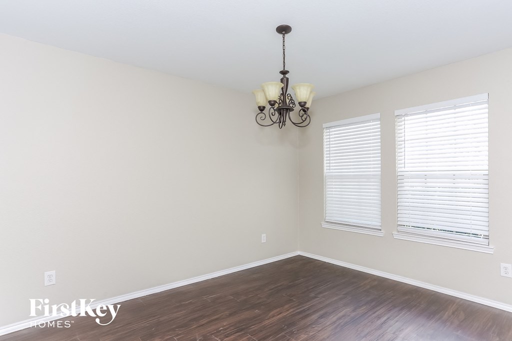 a bedroom with white walls and wood floors and a chandelier