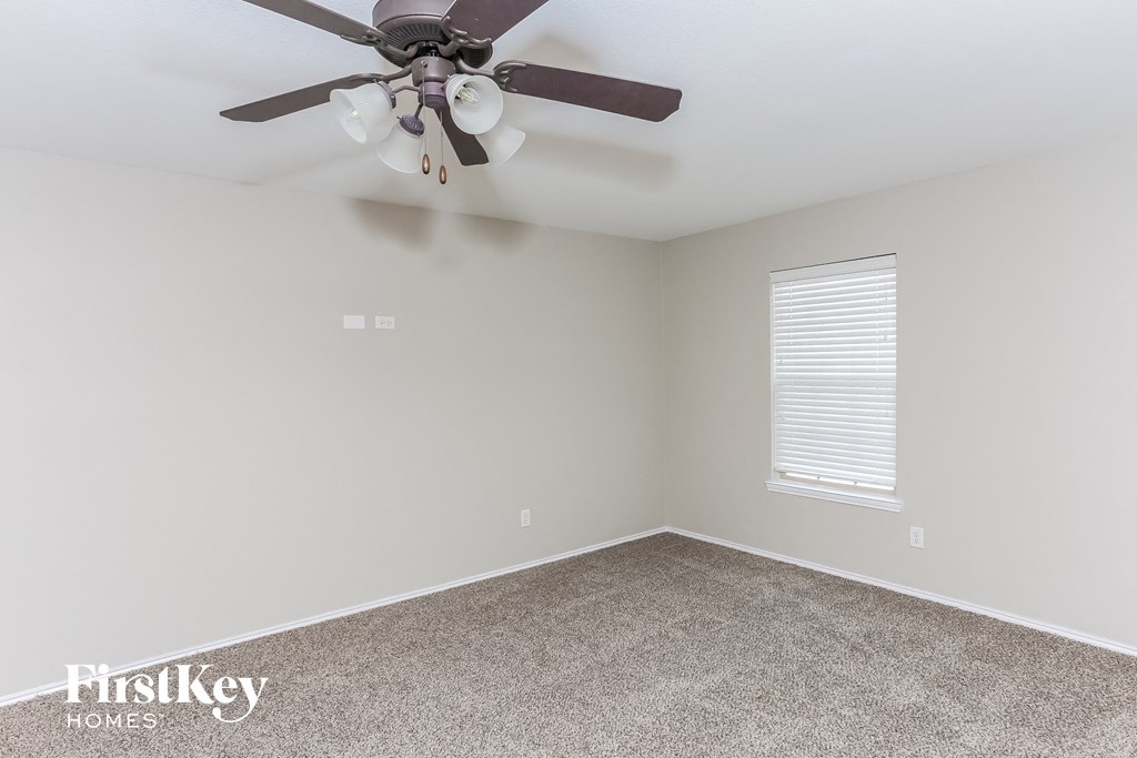 a bedroom with a ceiling fan and a carpet