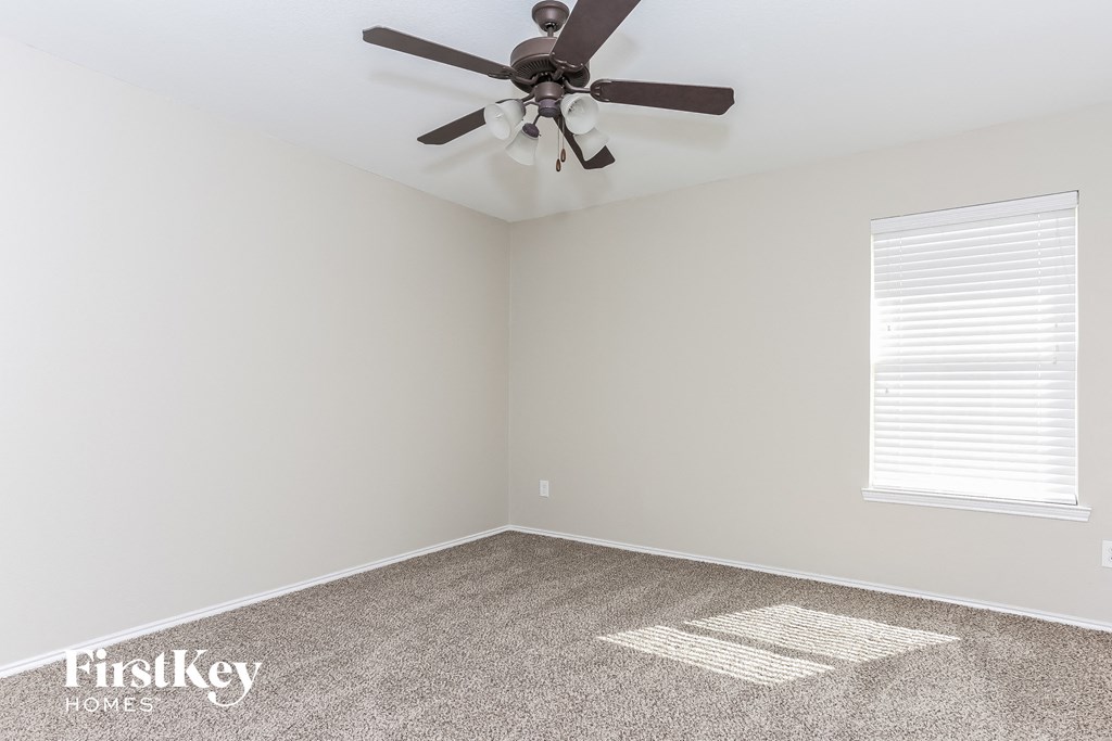a bedroom with a ceiling fan and a carpet