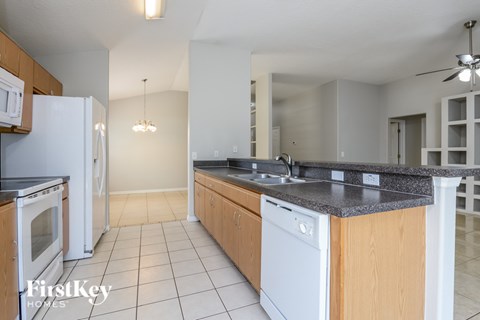 A kitchen with a white fridge and a black counter top.