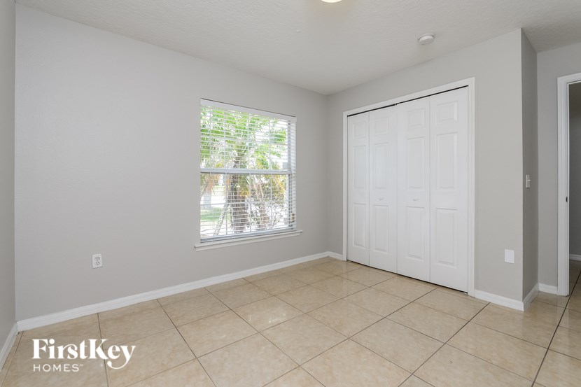 A room with a white door and a window with a view of trees.