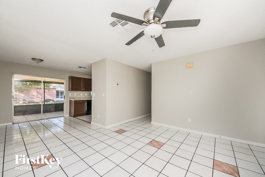 an empty living room with a ceiling fan and a tiled floor