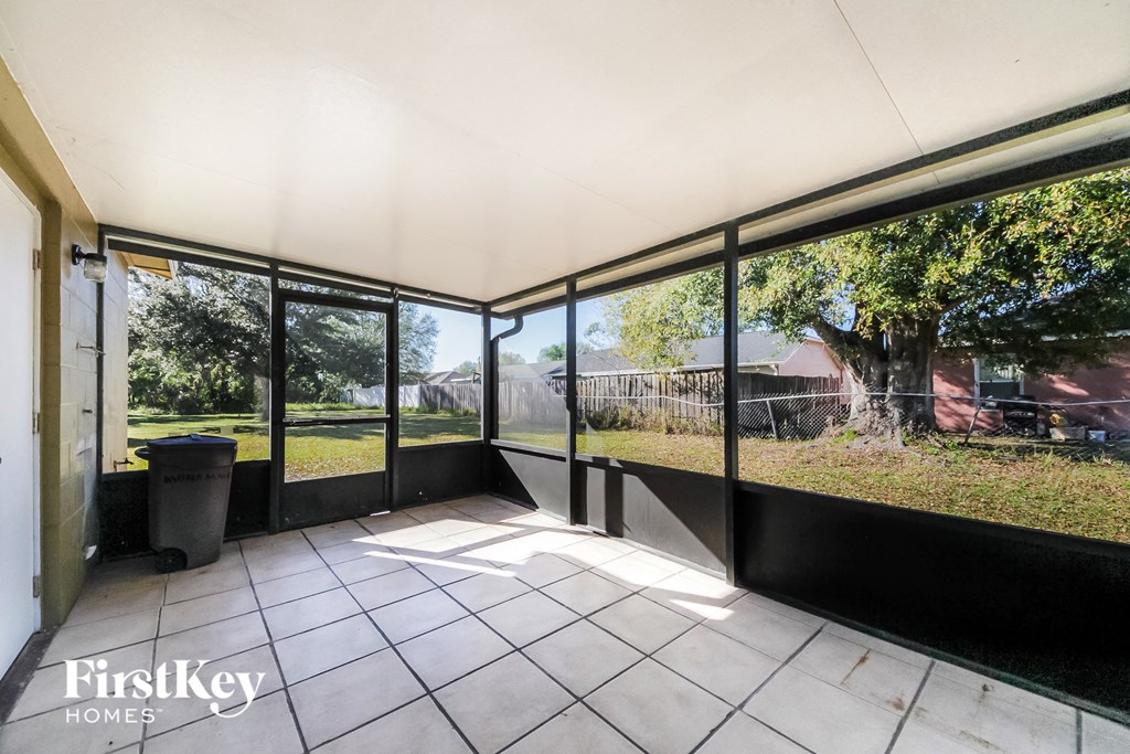 a screened in porch with large windows overlooking a yard
