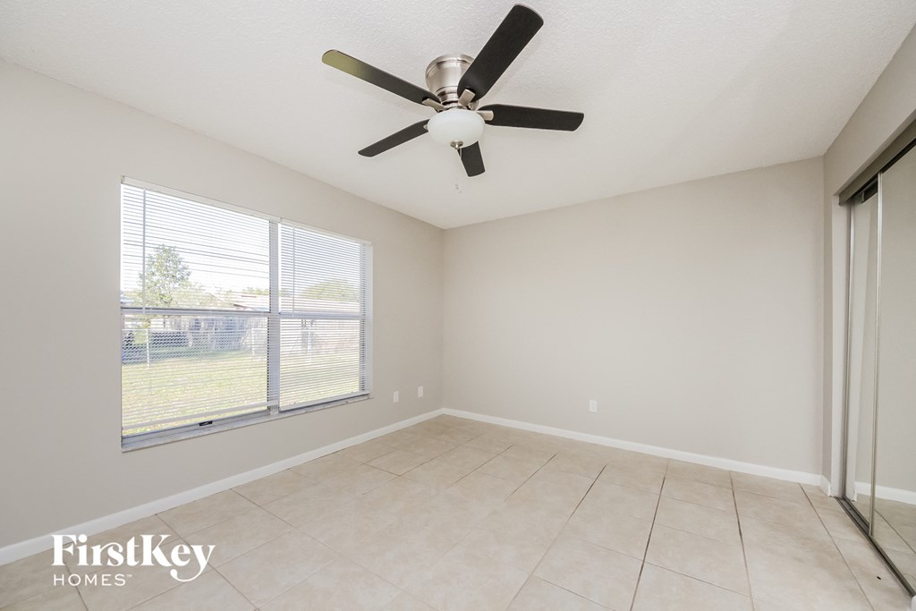 an empty living room with a ceiling fan and a window