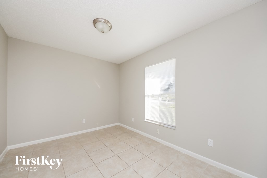 an empty living room with a large window and tiled floors