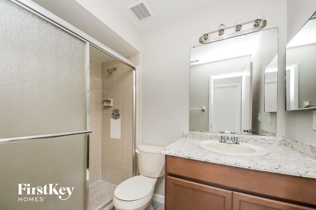 a bathroom with a shower toilet and sink and a mirror