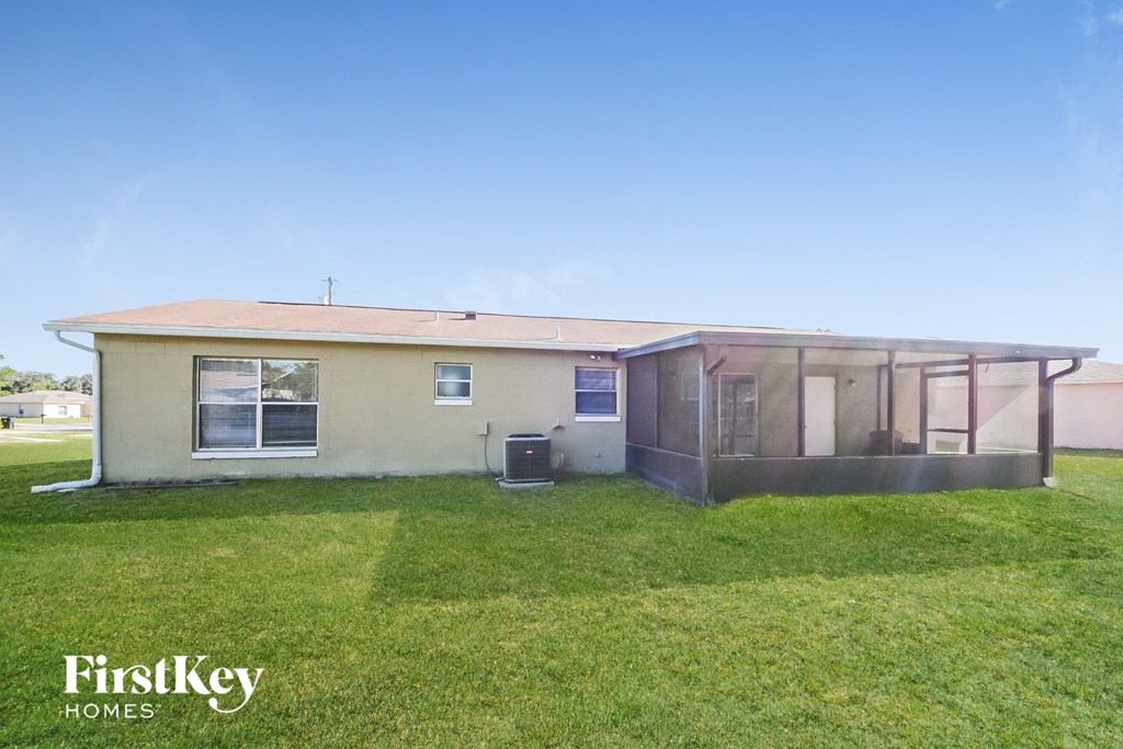 a small beige house with a grassy yard and a clear blue sky