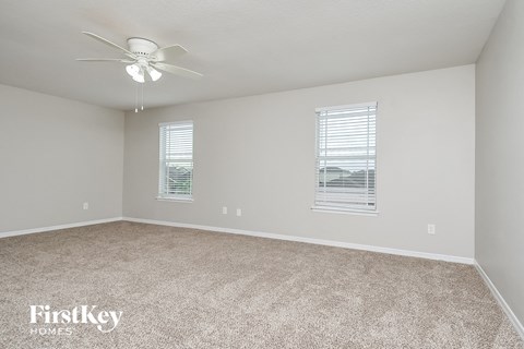 a spacious living room with carpet and a ceiling fan