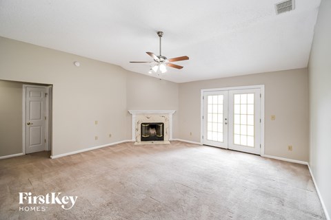 an empty living room with a fireplace and a ceiling fan