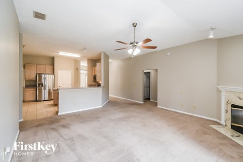 an empty living room with a fireplace and a ceiling fan