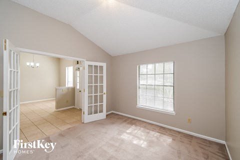 a dining room with a door to a kitchen and a window