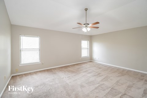 a spacious living room with a ceiling fan and a window