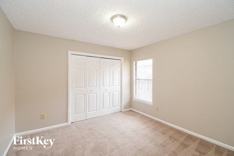 an empty living room with a white door and a window